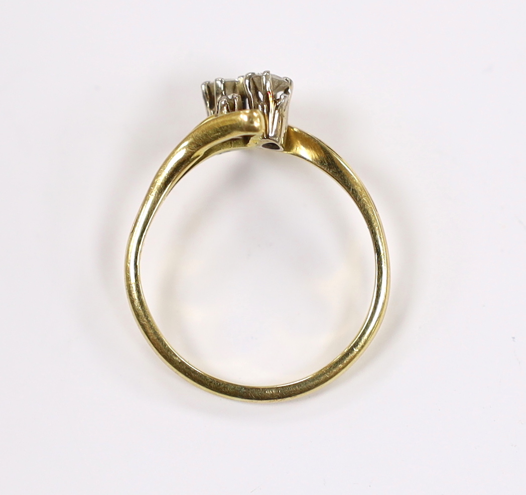 A yellow metal and graduated four stone diamond set crossover ring, size R, gross weight 3.4 grams.
